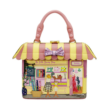 Handbag designed like a miniature sewing shop with a pink and yellow striped roof.