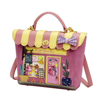 Pink and yellow handbag with sewing-themed design on a white background