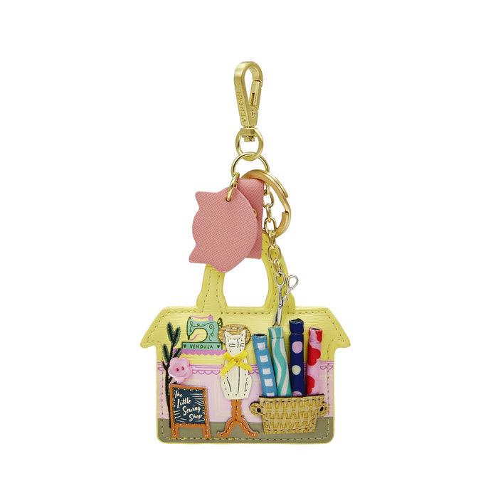 Keychain with a handbag design featuring a cat, books, and a pink owl on a white background.