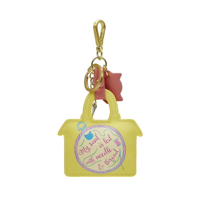 Yellow handbag-shaped keychain with pink bow and text on a white background
