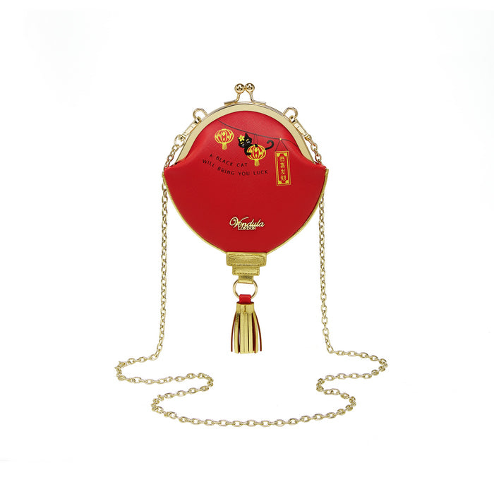 Red handbag with gold chain and tassel on a white background