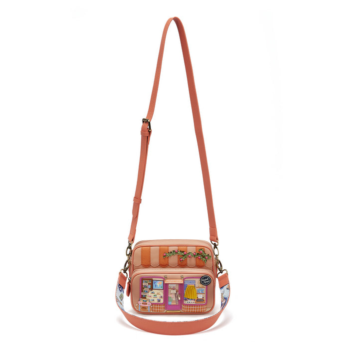 Pink crossbody bag with a patterned strap on a white background
