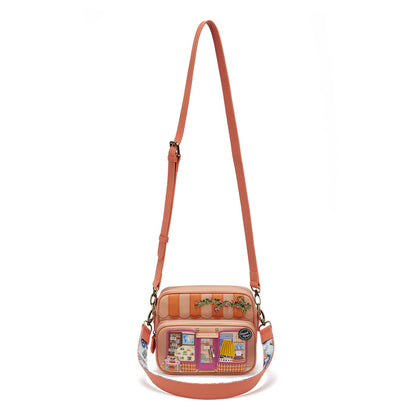 Pink crossbody bag with a patterned strap on a white background
