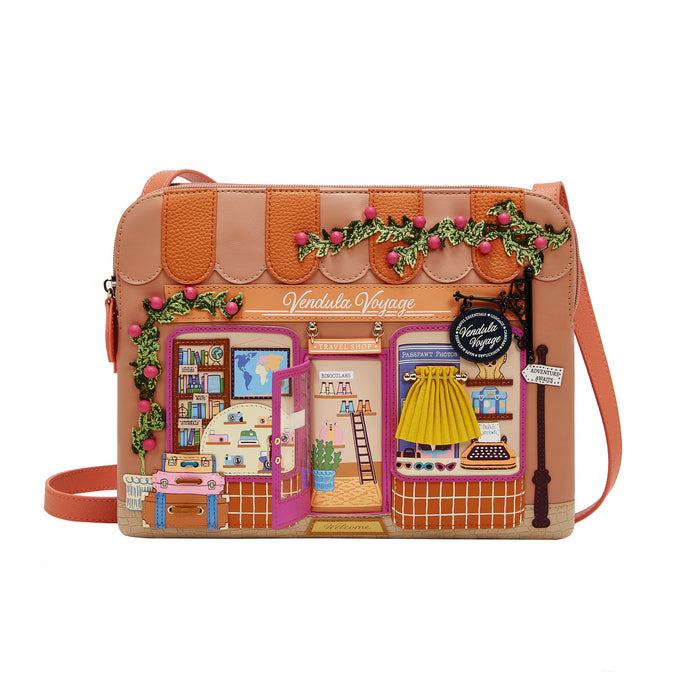 Crossbody bag with a detailed design of a store front and 'Vendula Voyage' branding.
