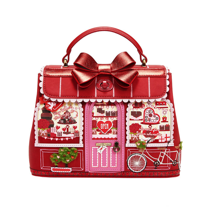 Red handbag with decorative elements and a large bow on a white background