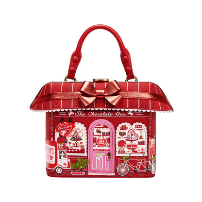 Red handbag designed like a chocolate box with a pink door and decorative elements on a white background
