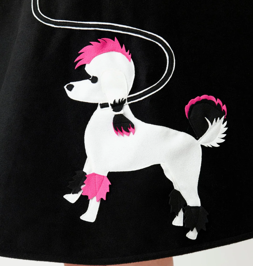 Black dress with a white dog illustration wearing pink hair and skirt on a black background