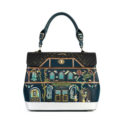 A structured handbag featuring a detailed illustration of 'The Gilded Cage' mansion facade, with a dark teal leather top handle, gold hardware, and a textured white base, shown against a plain white background.