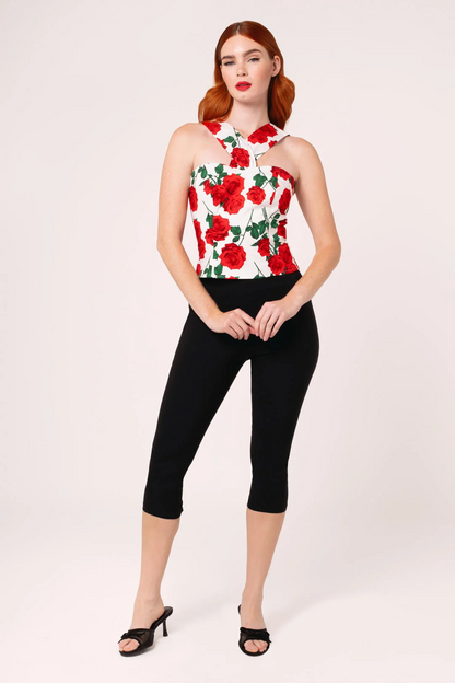 Woman wearing a floral top and black capri pants on a white background