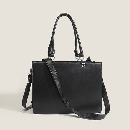Black handbag with a shoulder strap on a light beige background