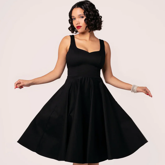 Woman wearing a black dress against a plain background
