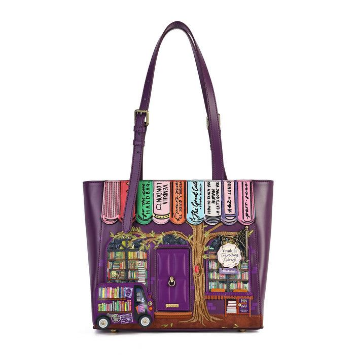 A purple leather tote bag featuring a whimsical, colorful illustration of a book-themed storefront with a tree, shelves, and books, shown against a plain white background.
