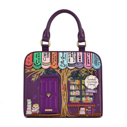 A purple handbag designed like a bookish library facade, featuring a purple handle, a purple front pocket with a gold-tone key ring, and a colorful illustrated design of book spines and bookshelves. A hanging tag reads 'Lewdula Trending Library'.