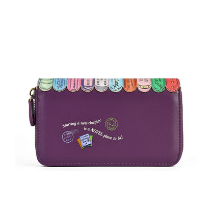 A purple zip-around wallet with a decorative top edge featuring colorful book spine designs and white script text on the front, shown on a plain white background.