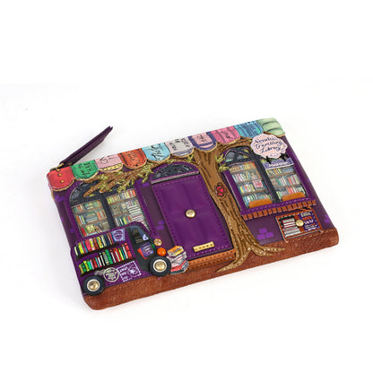 A purple zippered pouch featuring a whimsical bookshop illustration with a tree, colorful bookshelves, and a small purple book character, photographed on a white background.