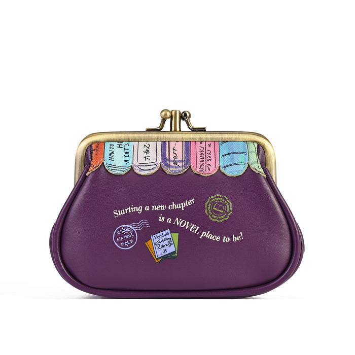 A purple kiss-lock clutch purse with a gold-tone metal frame and clasp. The front of the purse features a whimsical design with colorful book spines along the top, white script text reading 'Starting a new chapter is a NOVEL place to be!', and small travel-style postmarks and a book illustration.
