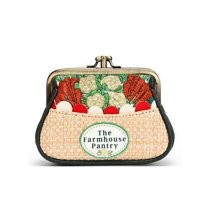 A small kiss-lock purse with a woven straw-like front and a printed vegetable-themed design on the back. The front has a round patch reading 'The Farmhouse Pantry.