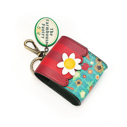 A small trifold wallet with a floral print and a red striped flap, attached to a metal keychain ring and a round 'The Farmhouse Farmacy' tag, shown on a white background.