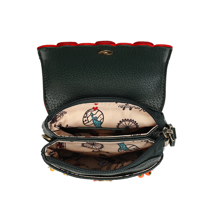 A dark green pebbled leather crossbody bag shown open, revealing a beige patterned interior with illustrations of the Statue of Liberty and the word 'Liberty.' The exterior has a scalloped red trim along the top edge and small red and orange bead accents near the bottom.