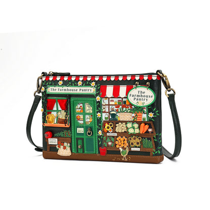 A rectangular shoulder bag with a whimsical embroidered 'The Farmhouse Pantry' storefront design, featuring a green door, red-and-white striped awning, and detailed market scene embroidery, shown on a white background.