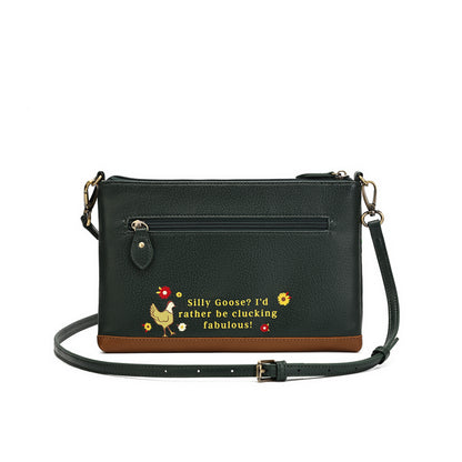 A black pebbled faux-leather crossbody bag with a brown base trim, featuring a front zip pocket and a humorous embroidered design with a rooster and the text 'Silly Goose? I'd rather be clucking fabulous!'.