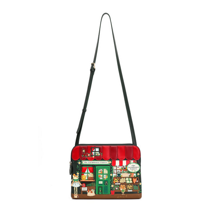A small crossbody bag featuring a detailed illustration of a vintage candy shop storefront on the front, complete with a red awning, green door, and colorful shop details. The bag has a black shoulder strap and is shown against a plain white background.