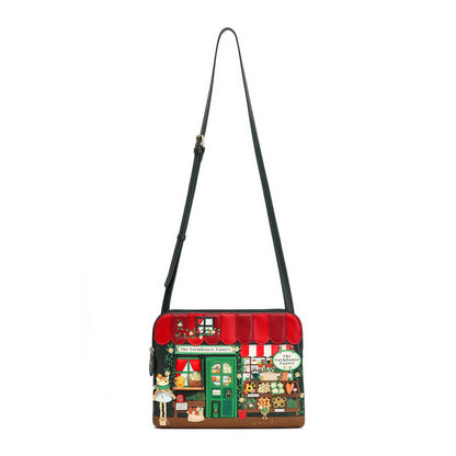 A small crossbody bag featuring a detailed illustration of a vintage candy shop storefront on the front, complete with a red awning, green door, and colorful shop details. The bag has a black shoulder strap and is shown against a plain white background.