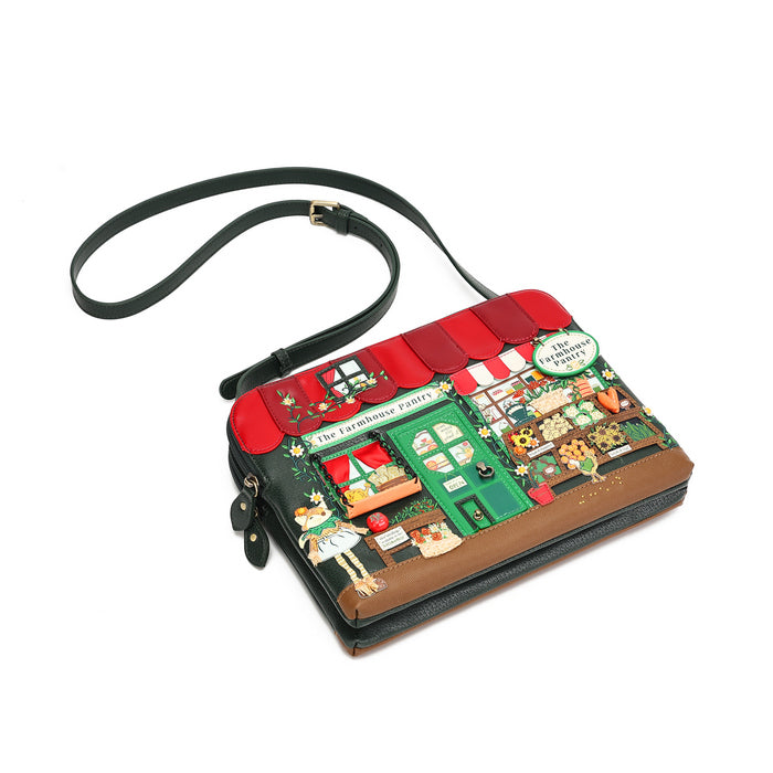 A rectangular shoulder bag with a black leather strap and a highly detailed, colorful illustration of a French bakery storefront on the front, set against a plain white background.