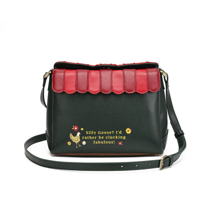 A black pebbled leather crossbody bag with a scalloped red leather top flap, featuring a yellow and red embroidered graphic on the front with the text 'Silly Goose? I'd rather be clucking fabulous!'.