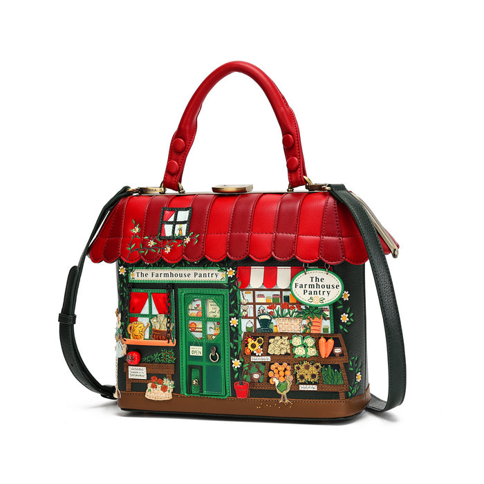 A structured handbag designed to look like a whimsical 'The Farmhouse Parlor' storefront, featuring a bright red faux-leather top handle and scalloped roof, with a detailed multicolor facade depicting a shop front, green door, and small decorative figures, shown on a white background.