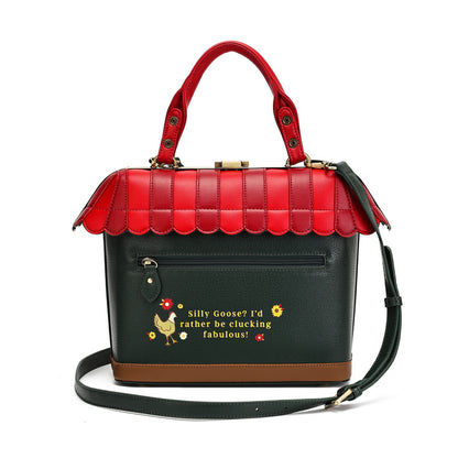 A structured handbag with a red roof and handles, a black body, and a brown base, featuring a decorative text print and a small rooster illustration on the front pocket.