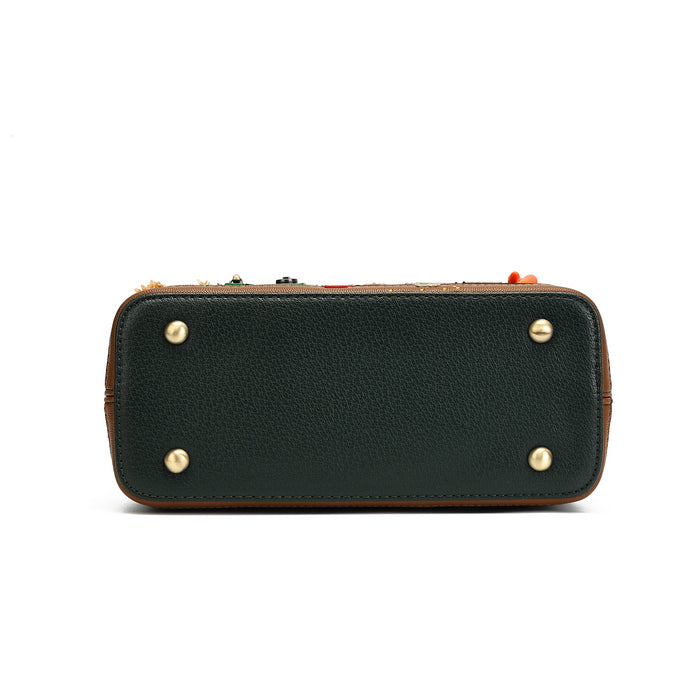 The bottom view of a dark forest green pebbled leather clutch or wallet-style handbag, featuring four brass rivets on the bottom corners and a decorative multicolor embroidered trim along the top edge.