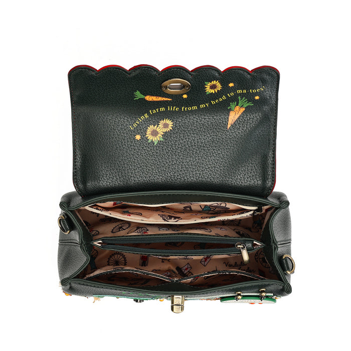 An open black pebbled leather handbag with a scalloped top edge, featuring embroidered carrots, sunflowers, and the phrase 'living farm life from my head to my toes' on the inside lid. The interior is lined with a brown patterned fabric and has multiple compartments.