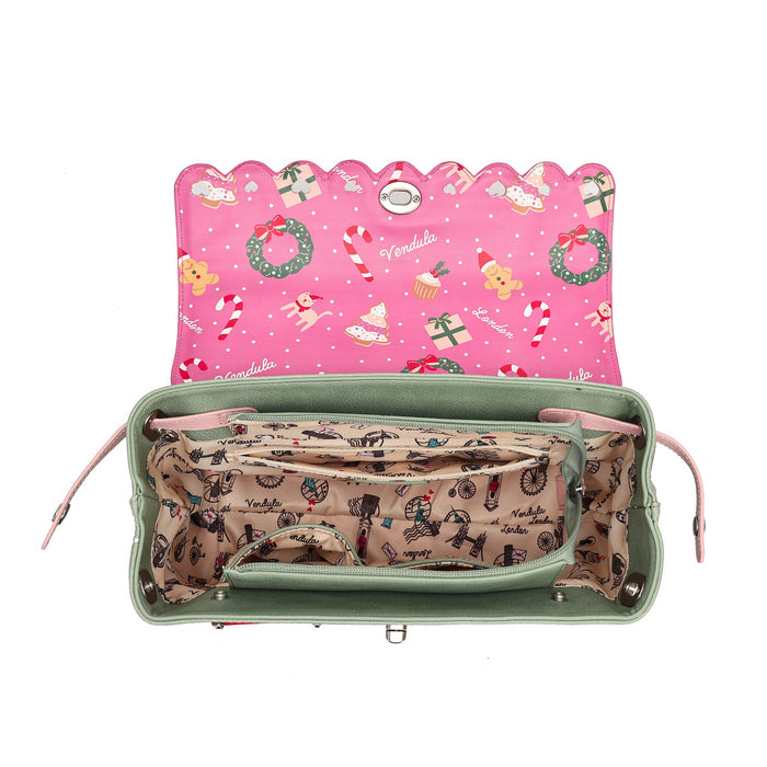 An open green handbag shown from above on a white background, with a pink holiday-themed interior lining and a beige patterned organizer pocket.
