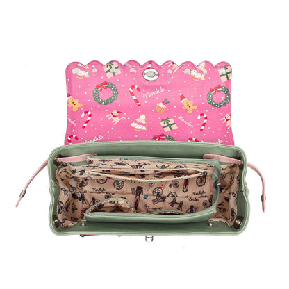 An open green handbag shown from above on a white background, with a pink holiday-themed interior lining and a beige patterned organizer pocket.