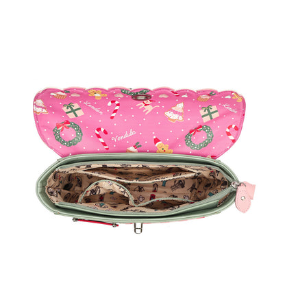 An open pink zippered pouch or organizer shown from above on a white background. The exterior is bright pink with a Christmas print featuring candy canes, green wreaths, Santa, and ornaments.