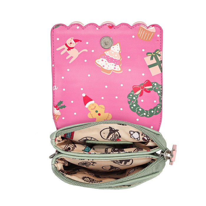 A pink zippered coin purse with a scalloped edge, featuring a Christmas-themed print on the exterior with a dog, Christmas tree, gift, wreath, and gingerbread man. The interior is lined with a beige patterned fabric and has a silver-tone snap button closure.