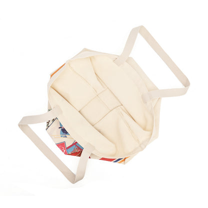 An off-white canvas tote bag with long shoulder straps, shown from an angled top-down view on a solid white background.