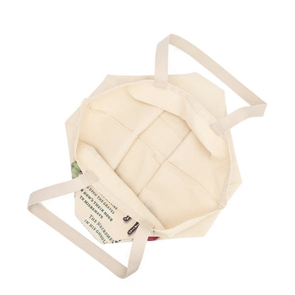 An off-white canvas tote bag with long shoulder straps, shown from an overhead angle on a solid white background.