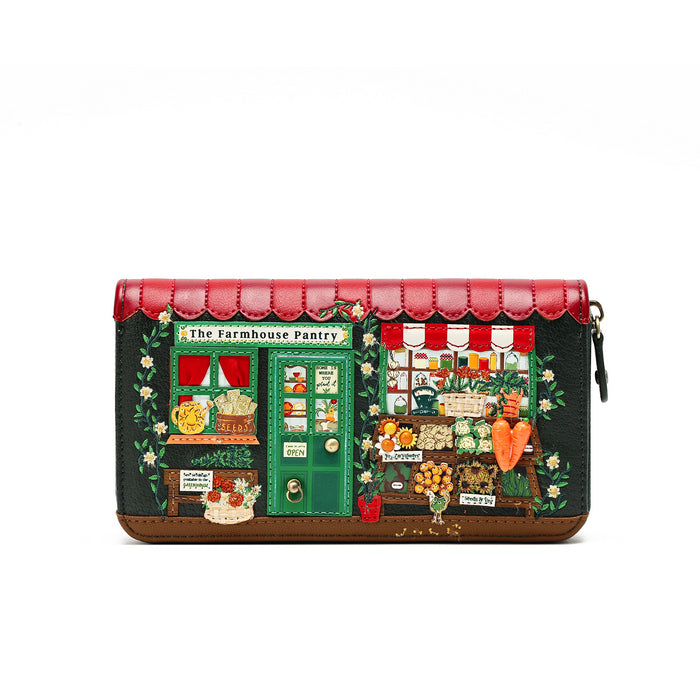 A long zip-around wallet featuring a detailed illustration of 'The Farmhouse Pantry' storefront on the front, with a red scalloped leather top, dark green body, brown base, and floral accents.