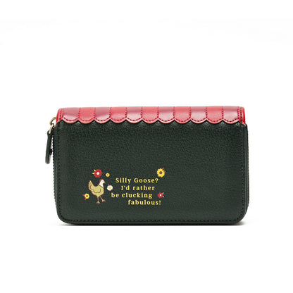 A dark green pebbled leather zip-around wallet with a scalloped pink top border, featuring a small embroidered chicken and the phrase 'Silly Goose? I'd rather be clucking fabulous!' in yellow and red on the front.