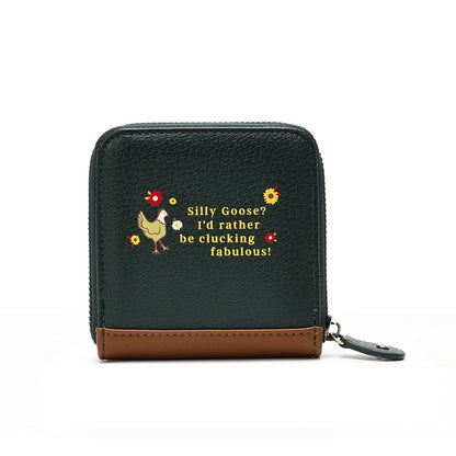 A dark green textured zip-around wallet with a brown leather base trim and a small embroidered design featuring a chicken, flowers, and the text 'Silly Goose! I'd rather be clucking fabulous!'.