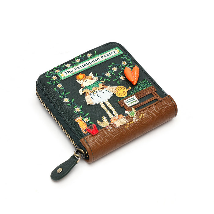 A small zip-around wallet with a dark green front featuring a colorful embroidered-style illustration of a cat in a kitchen and the text 'The Farmhouse Pantry,' plus a brown leather side pocket, shown on a white background.
