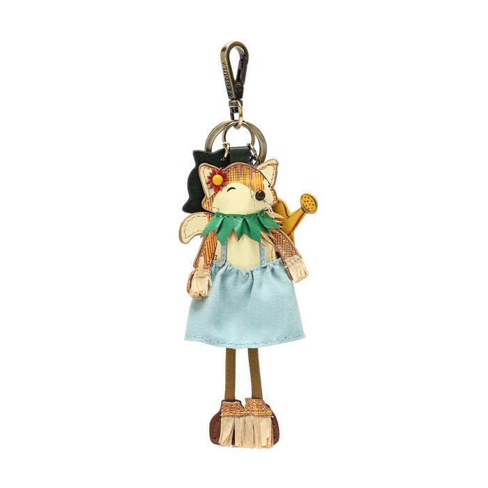 A whimsical keychain charm shaped like a fairy girl, featuring a light blue dress, green collar, brown legs, and a gold watering can, attached to a black cat-shaped clip on a white background.