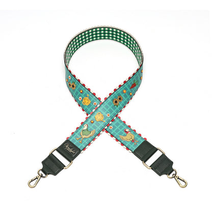A fabric shoulder strap with a green and white gingham checkered inner lining, a teal patterned outer fabric featuring ducks, flowers, and red scalloped edges, finished with dark green leather ends and gold-tone swivel clips.