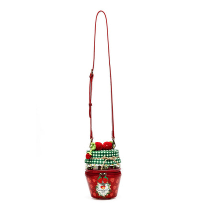 A red Christmas-themed crossbody bag shaped like a cupcake, featuring a red body with a white Santa decoration, a green and white checkered ribbon, and red pom-pom strawberries on top, complete with a long red shoulder strap.