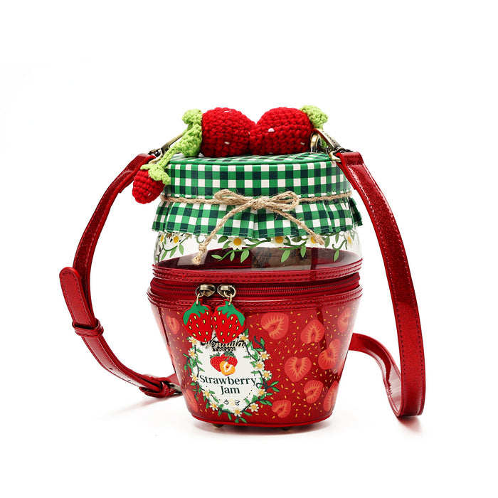 A strawberry-themed clear plastic bucket bag with a red zipper, decorated with a red strawberry pattern, a green and white gingham check top, a small bow, and a crocheted red strawberry decoration on top. It features a red shoulder strap and a hanging charm that reads 'Strawberry Jam'.