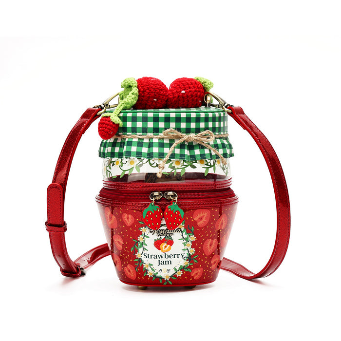 A red shoulder bag designed to look like a strawberry jam jar, featuring a red body with strawberry patterns, a green and white checkered lid, a clear middle section with daisy floral print, and decorative red and green crochet strawberries on top.