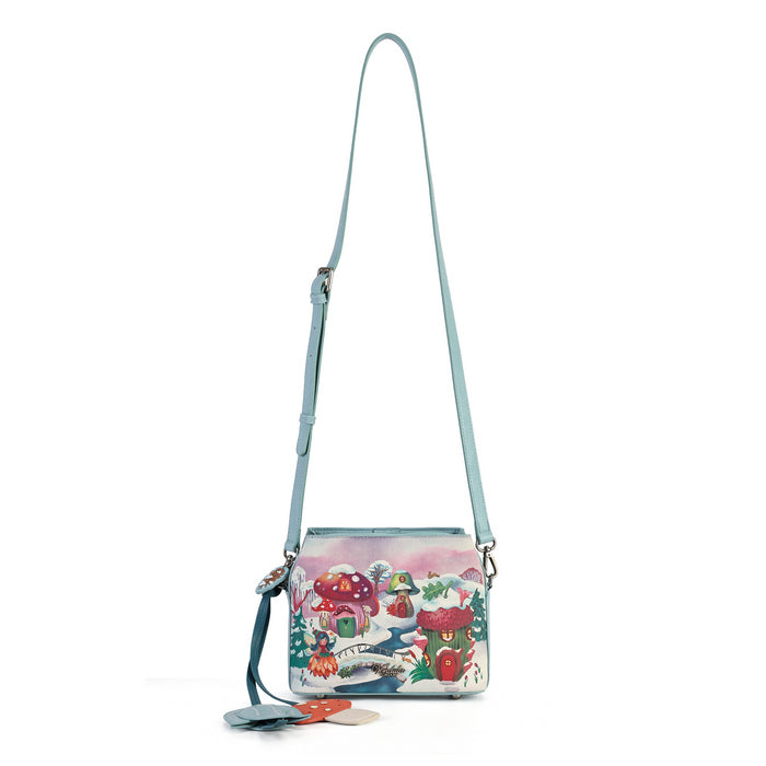 A small crossbody bag with a light blue strap and a colorful winter mushroom illustration on the front, shown against a plain white background.