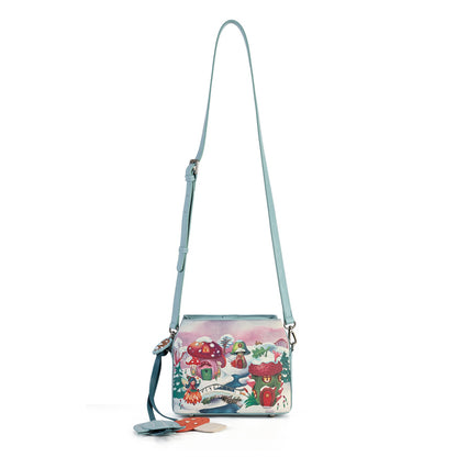 A small crossbody bag with a light blue strap and a colorful winter mushroom illustration on the front, shown against a plain white background.